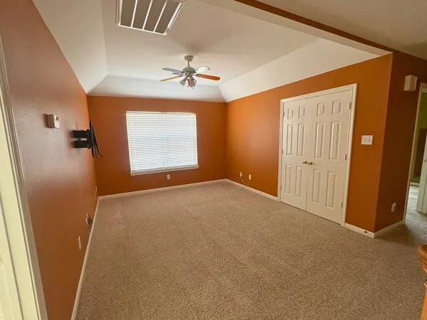 an empty room with windows and fan
