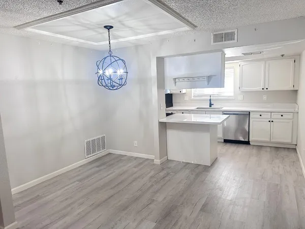 a kitchen with cabinets wooden floor and a chandelier