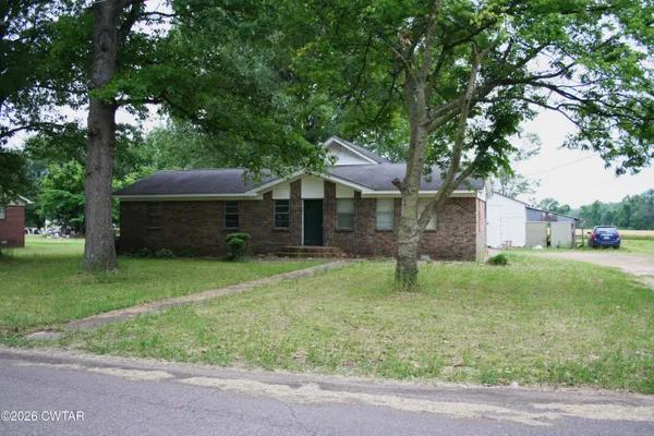 a backyard of a house with plants and large tree