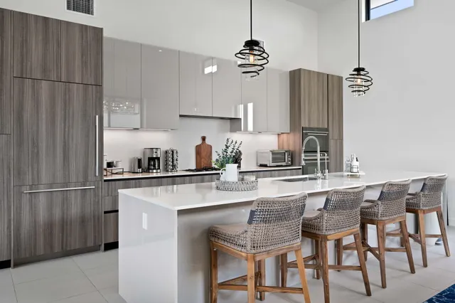 a kitchen with stainless steel appliances granite countertop a sink a stove a refrigerator and chairs