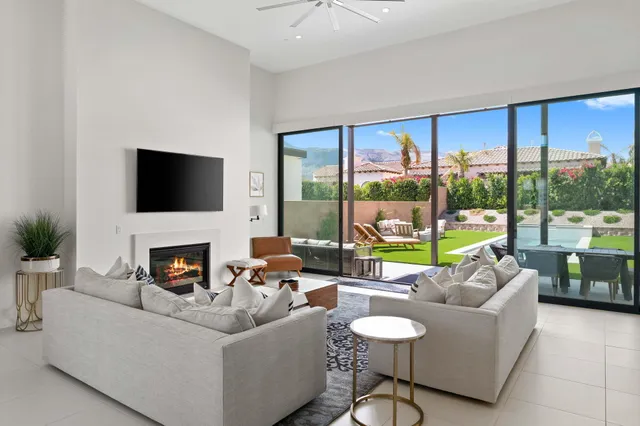 a living room with furniture a fireplace and a large window with garden view