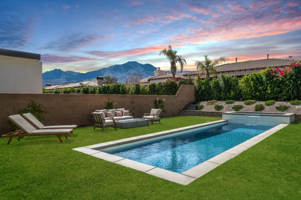 a view of a swimming pool with lounge chairs in back yard