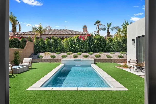 a view of a swimming pool with a patio and a yard