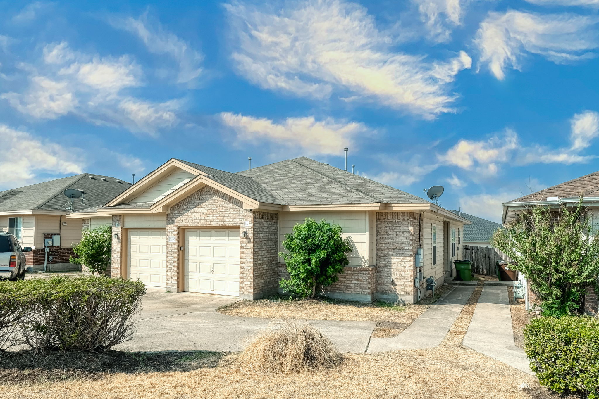 Ranch-style house with brick siding, an attached garage, driveway, and a shingled roof
