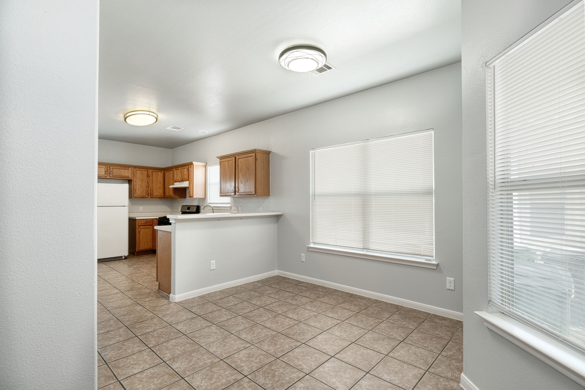 2802 Southampton Way, Unit A Round Rock, TX 78664 - Photo 3 of 13 Kitchen featuring freestanding refrigerator, light countertops, light tile patterned floors, wood finish cabinets, and a peninsula
