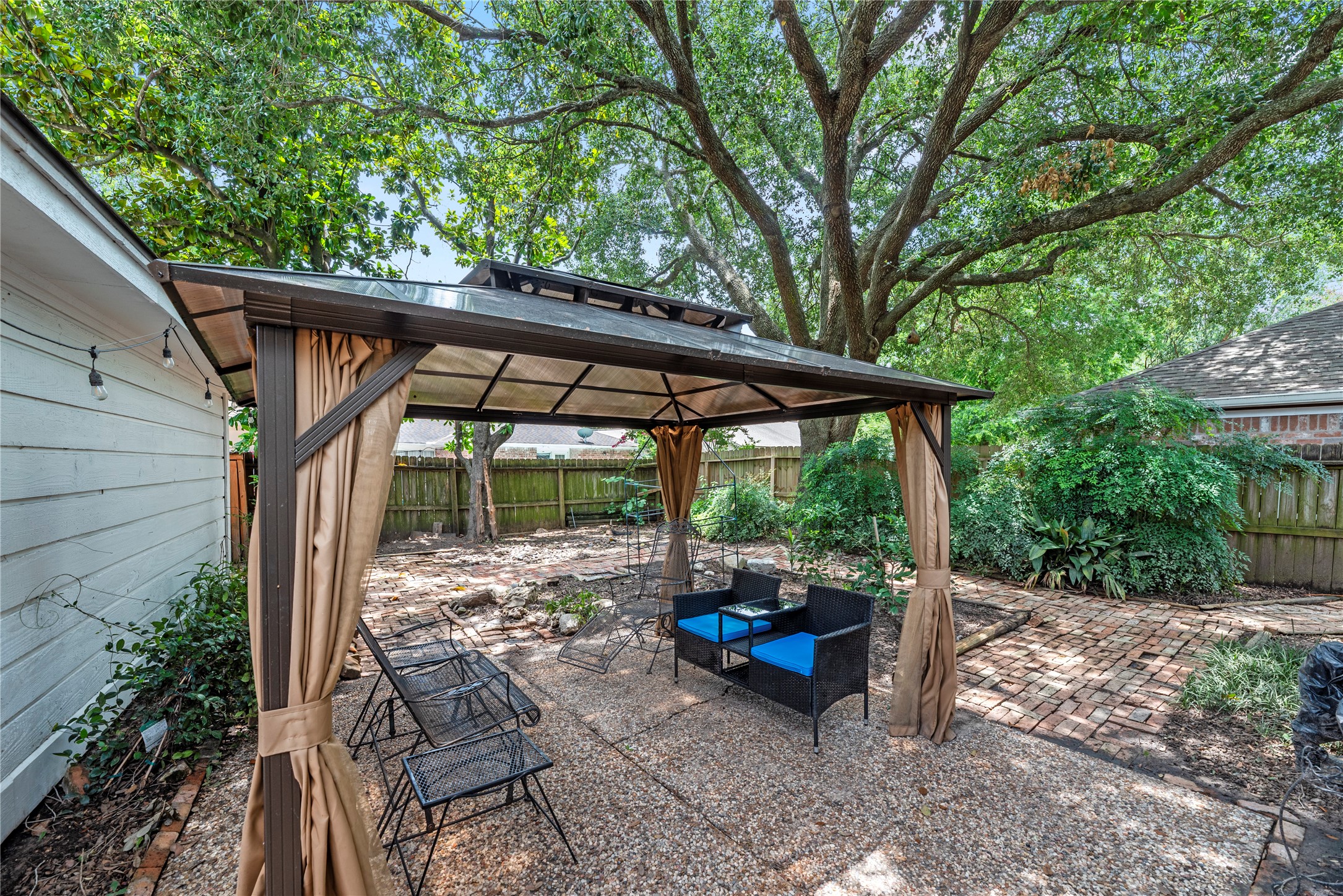14203 Wickersham Lane Houston, TX 77077 - Photo 20 of 25 Shaded backyard retreat boasting an extensive brick patio surface underneath a canopy of grand, mature trees—perfect for outdoor dining and entertaining under gazebo.