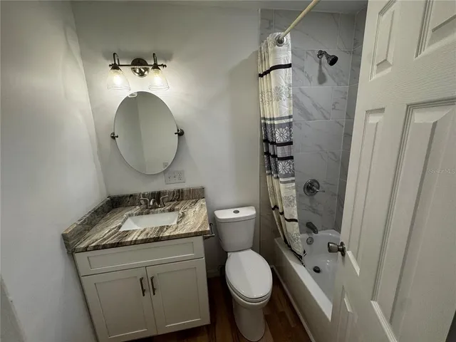a bathroom with a granite countertop sink toilet mirror vanity and shower