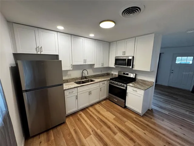 a kitchen with granite countertop a refrigerator stove top oven and sink