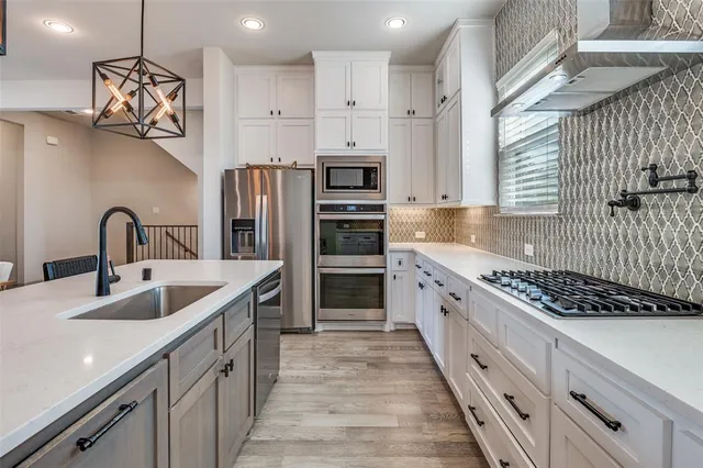a kitchen with stainless steel appliances granite countertop a sink and a stove top oven