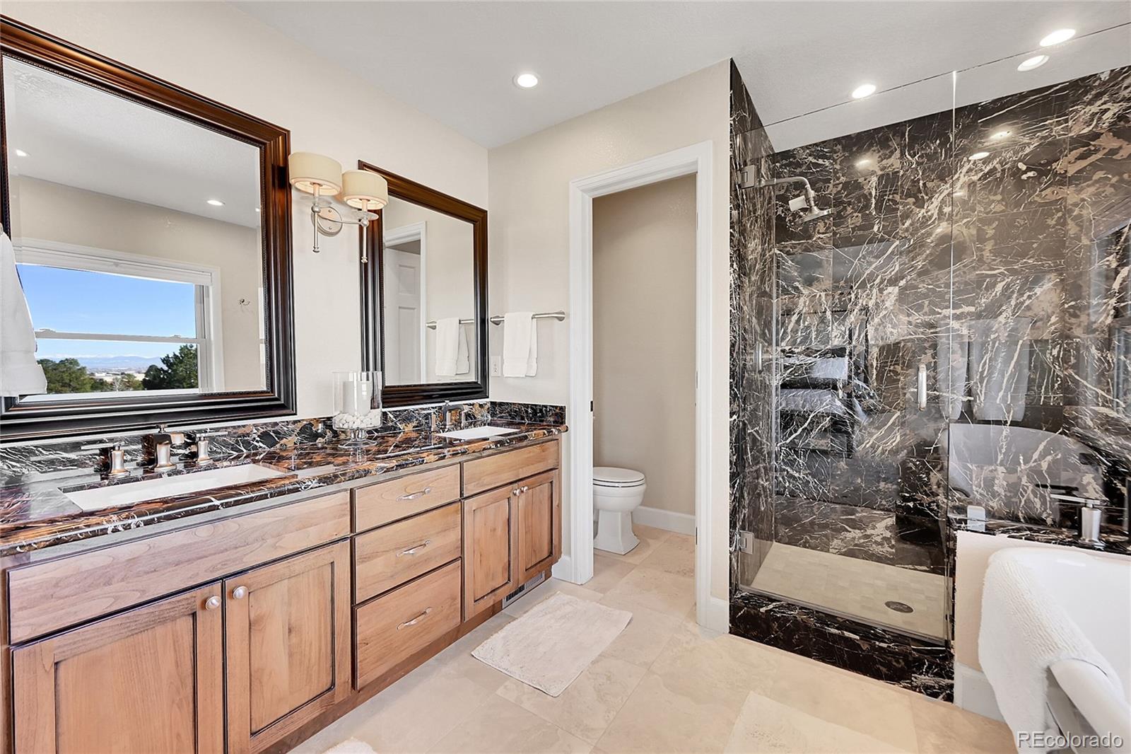8717 Thunderbird Circle Parker, CO 80134 - Photo 27 of 50 a bathroom with a double vanity sink a toilet a mirror and shower