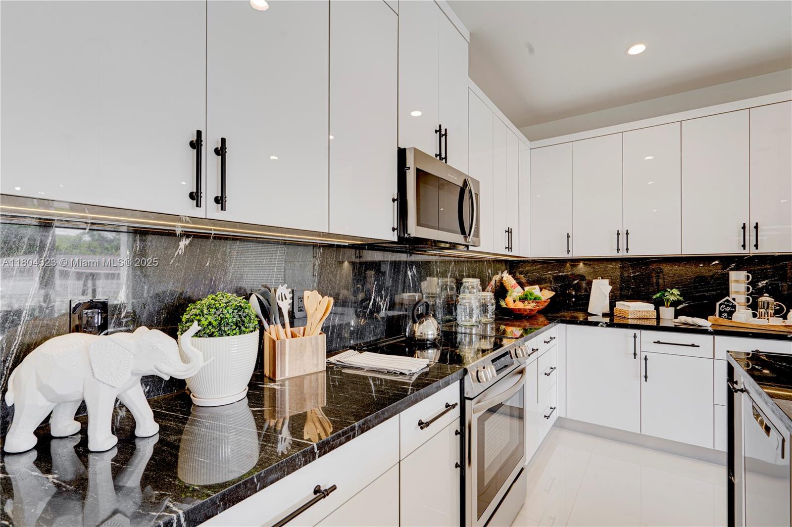 1805 Northwest 22nd Court Miami, FL 33125 - Photo 12 of 58 a kitchen with stainless steel appliances kitchen island granite countertop a table chairs in it and white cabinets