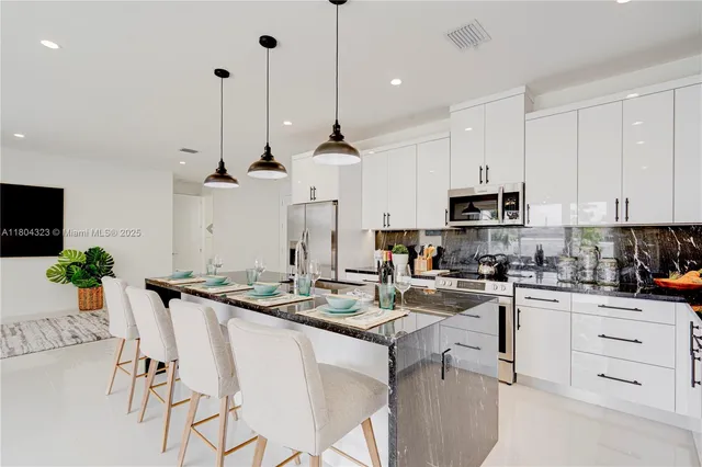 a kitchen with stainless steel appliances kitchen island granite countertop a table chairs and white cabinets
