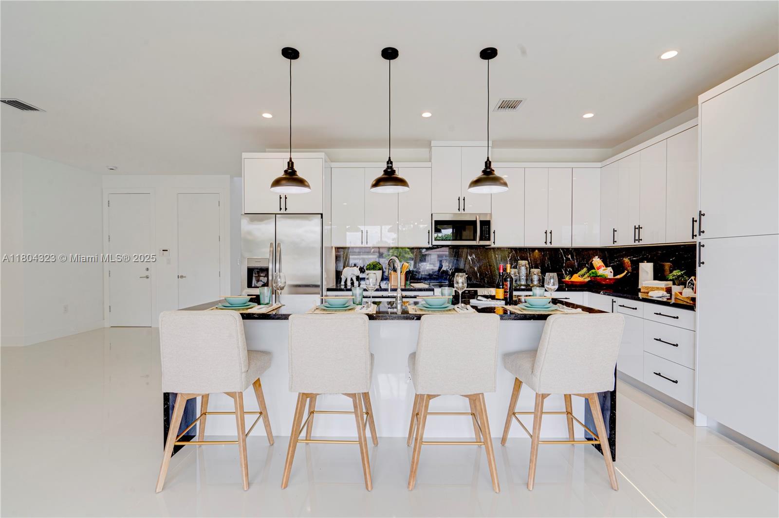 1805 Northwest 22nd Court Miami, FL 33125 - Photo 17 of 58 a kitchen with stainless steel appliances kitchen island granite countertop a table chairs and white cabinets