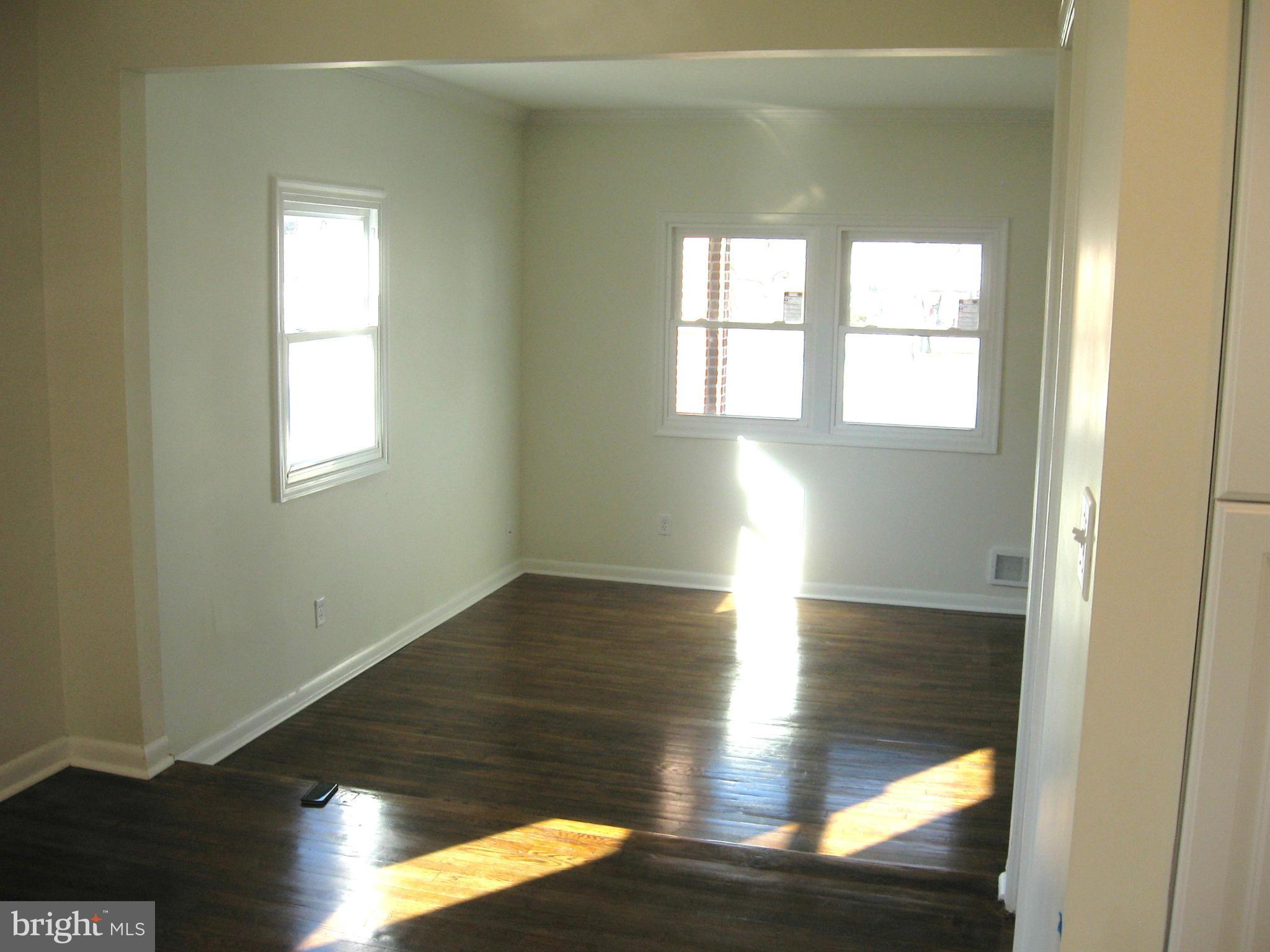 8245 Del Haven Road Baltimore, MD 21222 - Photo 7 of 29 an empty room with wooden floor and windows