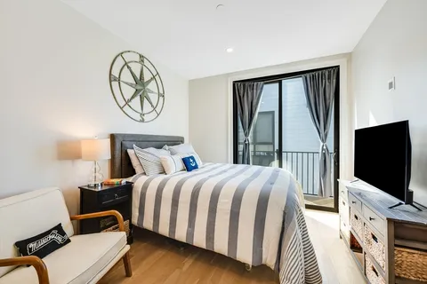 a bedroom with a bed tv and a window