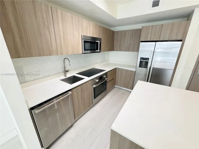 a kitchen with a sink a microwave a refrigerator and cabinets