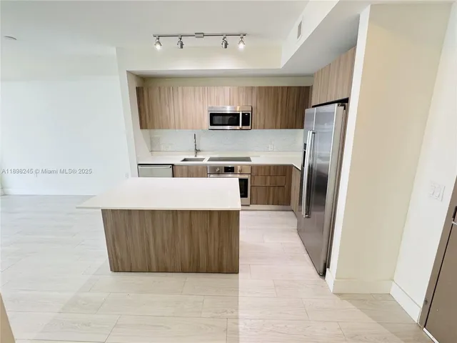 a kitchen with stainless steel appliances a stove top oven a refrigerator a sink and dishwasher