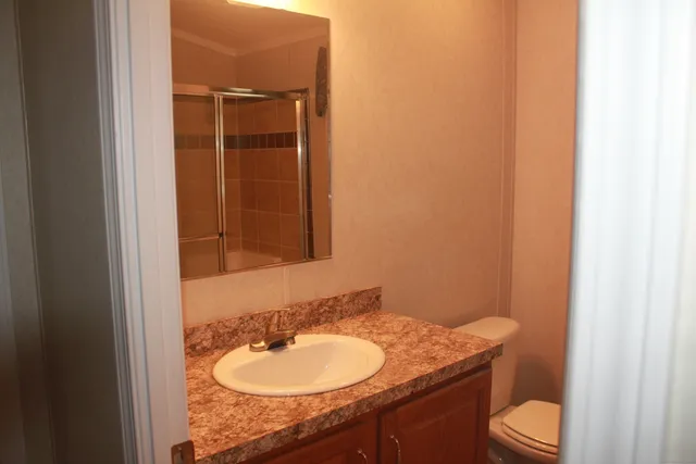 a bathroom with a granite countertop sink toilet and mirror