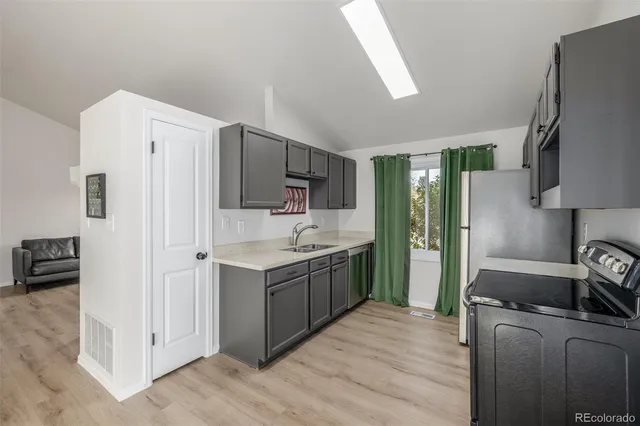 a kitchen with a sink a refrigerator and a stove top oven