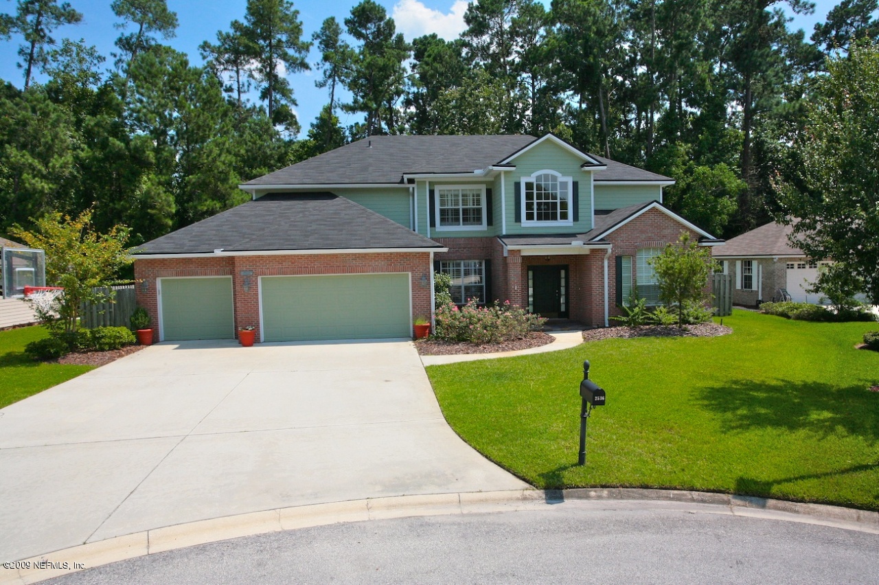 a front view of a house with a garden and trees