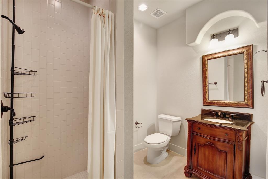 4111 Rawlins Street, Unit 403 Dallas, TX 75219 - Photo 5 of 23 Bathroom featuring a shower with white subway tile surround, a decorative vanity with a dark countertop and undermount sink, a framed mirror, and recessed lighting