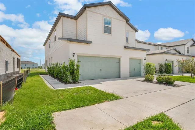 a view of a white house next to a yard and large trees