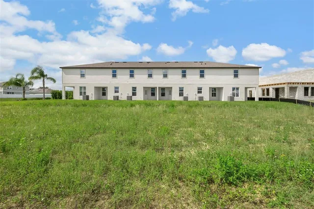 a view of house with a big yard and potted plants