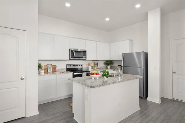 a kitchen with stainless steel appliances granite countertop a refrigerator sink stove microwave and cabinets