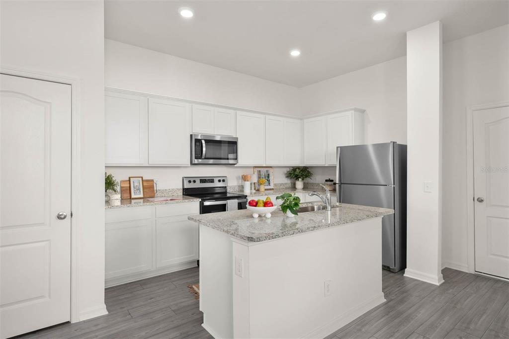 685 Poppy Lane Dundee, FL 33838 - Photo 7 of 31 a kitchen with stainless steel appliances granite countertop a refrigerator sink stove microwave and cabinets