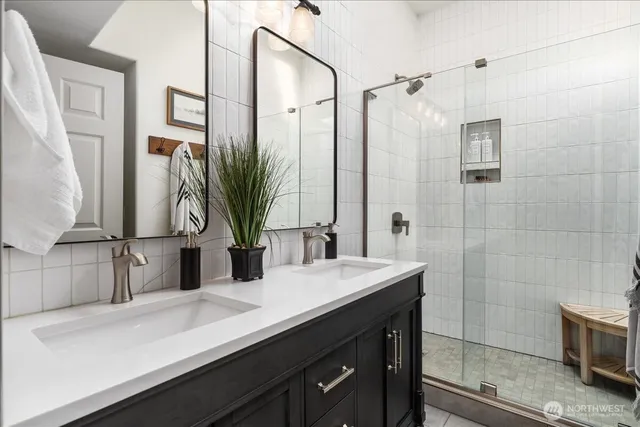 a bathroom with a double vanity sink a mirror and a shower