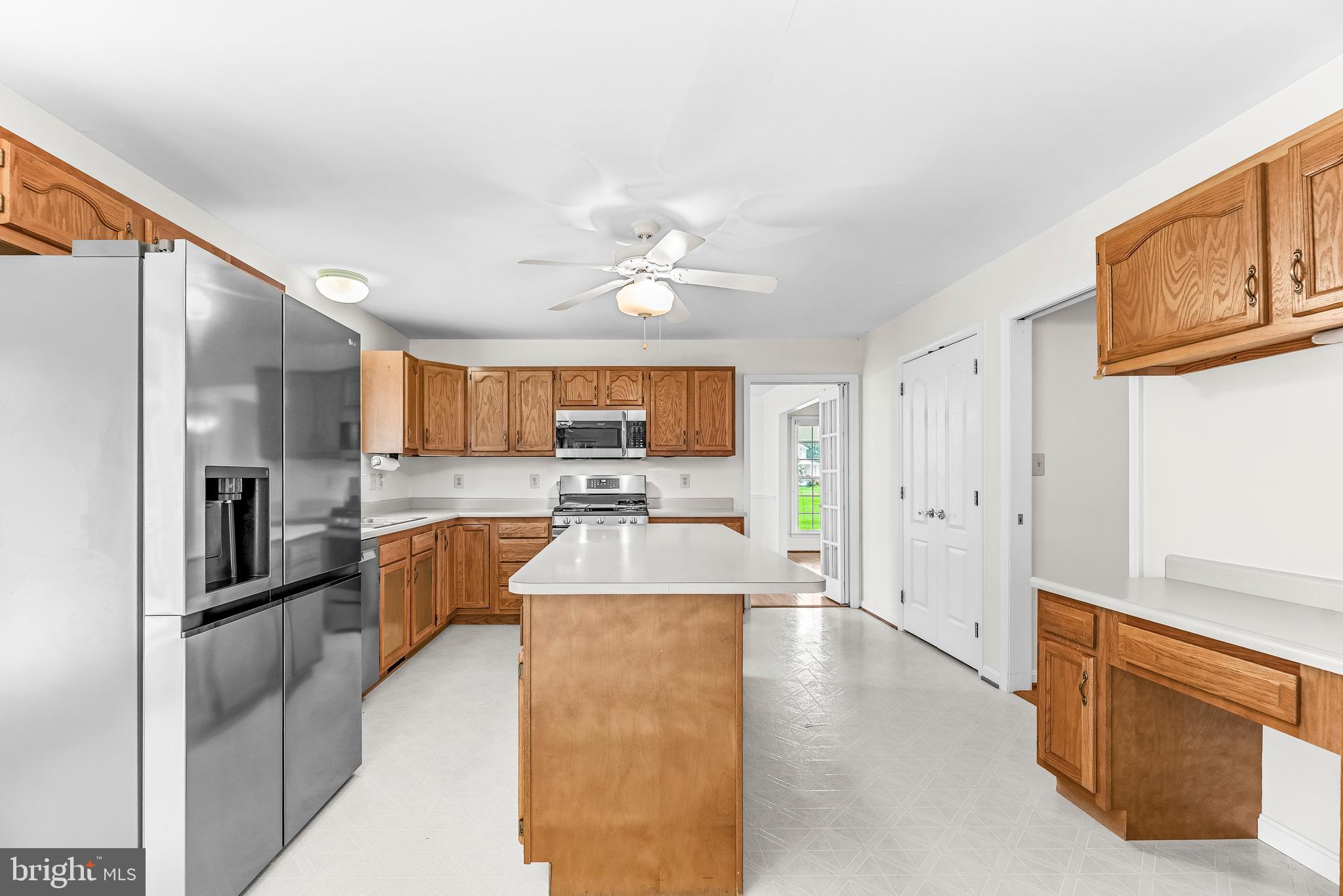 5965 Ketch Road Prince Frederick, MD 20678 - Photo 18 of 56 a large kitchen with kitchen island granite countertop a refrigerator a stove a sink a dining table and chairs with wooden floor