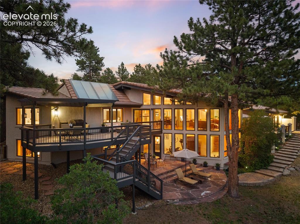 12730 Bridle Bit Road Colorado Springs, CO 80908 - Photo 43 of 50 Multi-level deck and patio area featuring a stone patio, extensive window array, upper covered deck, and a tiered stone pathway