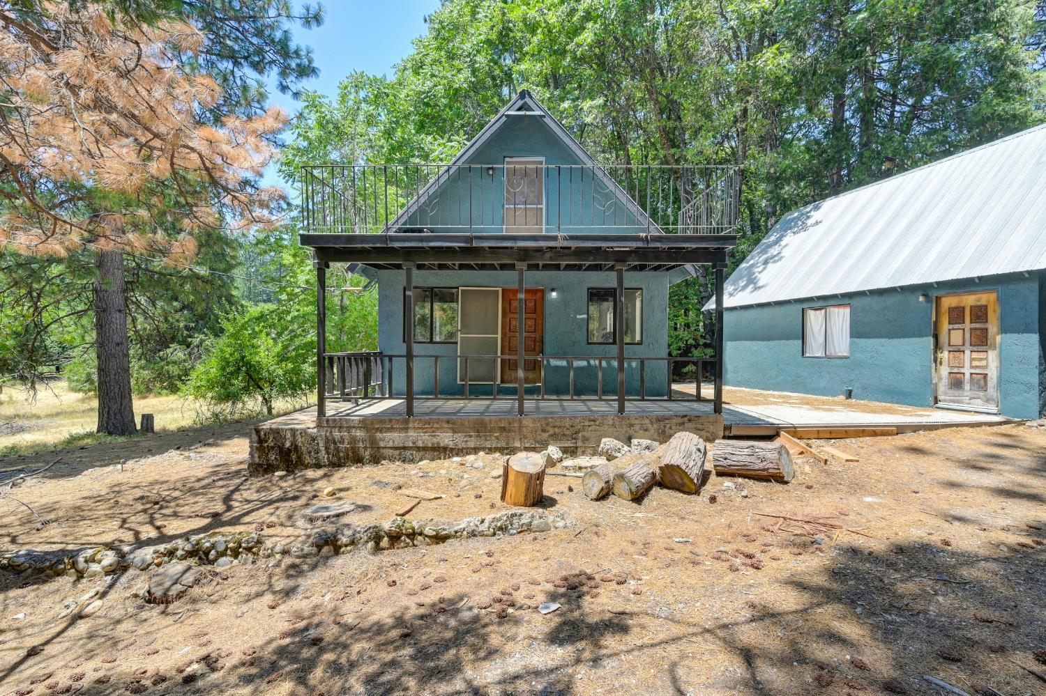 a front view of a house with a dirt yard and a large tree