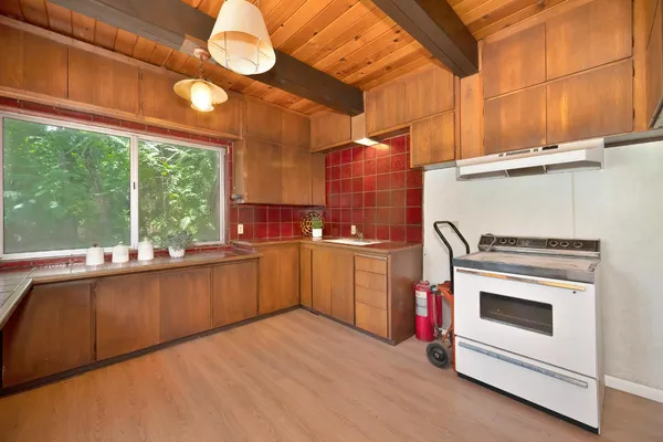 a kitchen with a stove and white cabinets with wooden floor