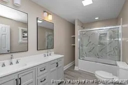 a bathroom with a granite countertop sink a toilet a mirror and shower