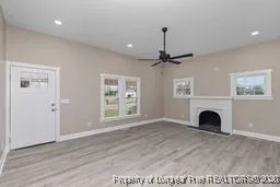 a view of an empty room with a fireplace and wooden floor