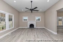 a view of a livingroom with a fireplace a ceiling fan and windows