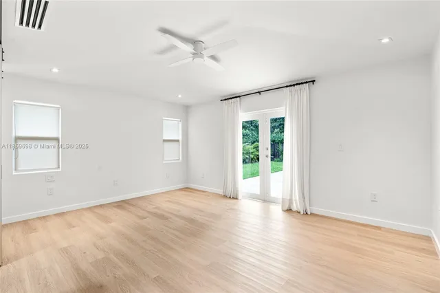 an empty room with wooden floor fan and windows