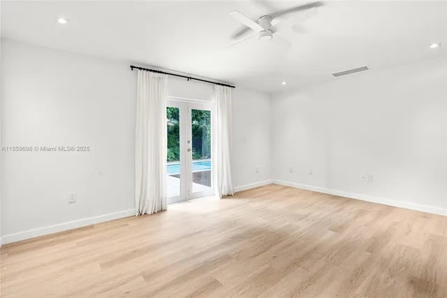 a view of an empty room with wooden floor and a ceiling fan