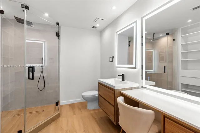a bathroom with a granite countertop sink a toilet a mirror and shower