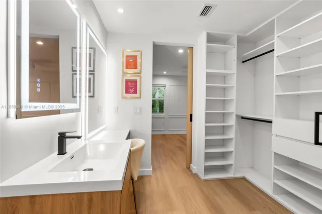 a view of a hallway to a livingroom with wooden floor and windows