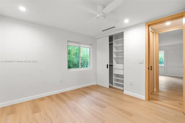 an empty room with wooden floor closet and windows