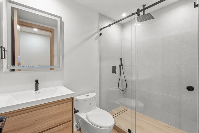a bathroom with a toilet sink vanity and shower