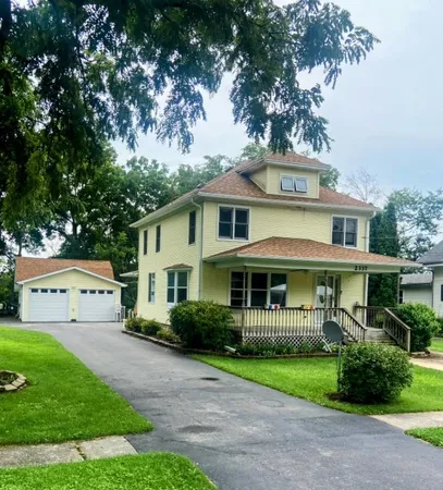 a view of a white house with a big yard and potted plants