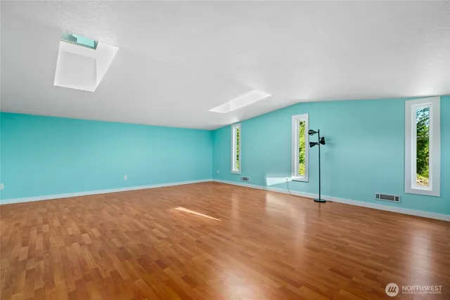 a view of an empty room with window and wooden floor