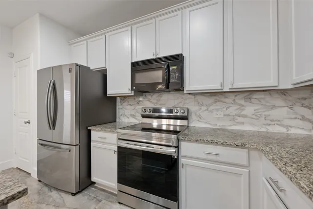 a kitchen with stainless steel appliances white cabinets and a granite counter top