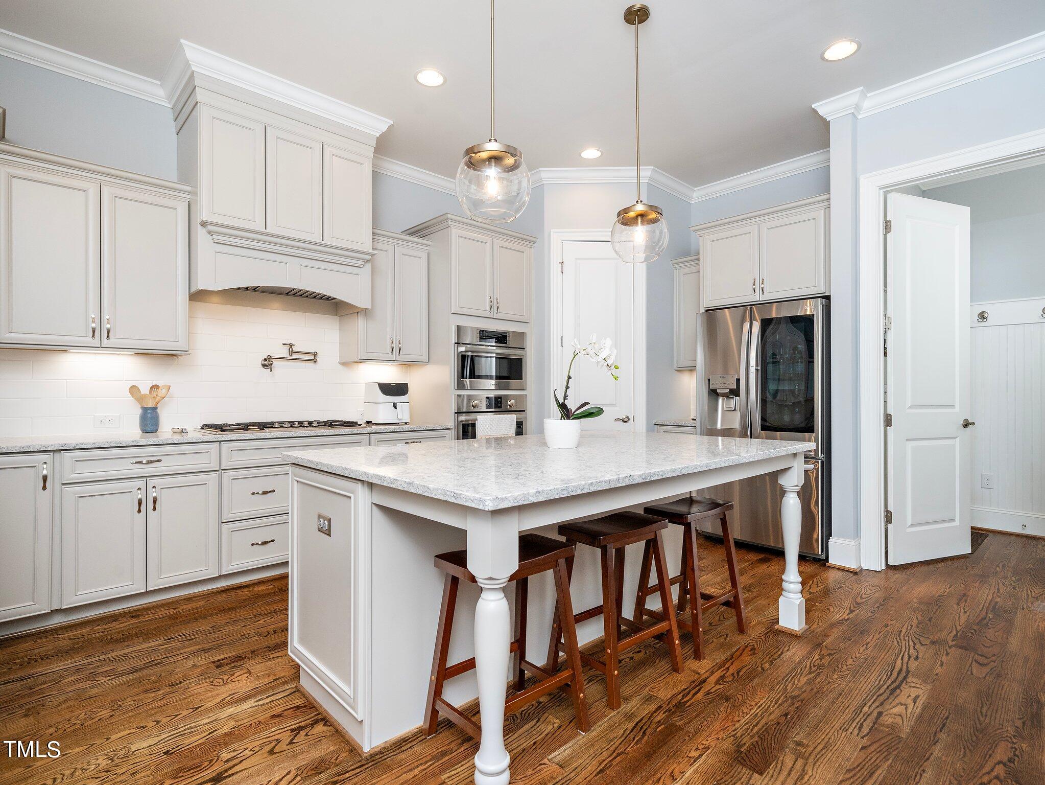 7733 Wilderness Road Raleigh, NC 27613 - Photo 16 of 37 a kitchen with stainless steel appliances granite countertop a sink a stove a refrigerator and island with wooden floor