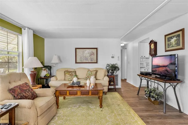 a living room with furniture flat screen tv and a large window