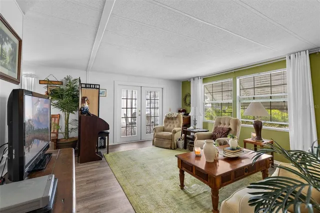 a living room with furniture flat screen tv and a large window