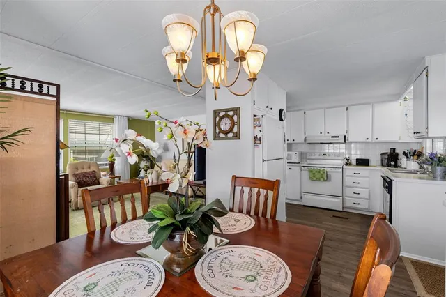 a dining room with wooden floor a chandelier a wooden table and chairs